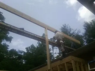 Carpenter setting a ridge beam over a new addition frame — Ice Dam Removal by Roofing Brothers in Leslie