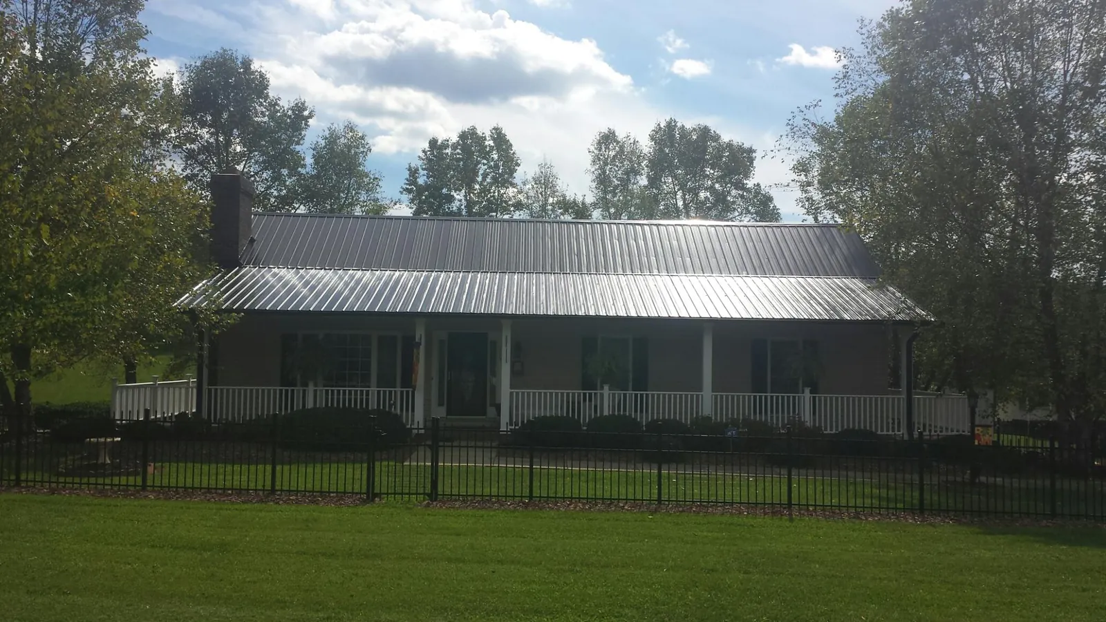 Gray metal roof on a brick ranch with a full width front porch — Gutter Guard Installation work by our crew in Leslie