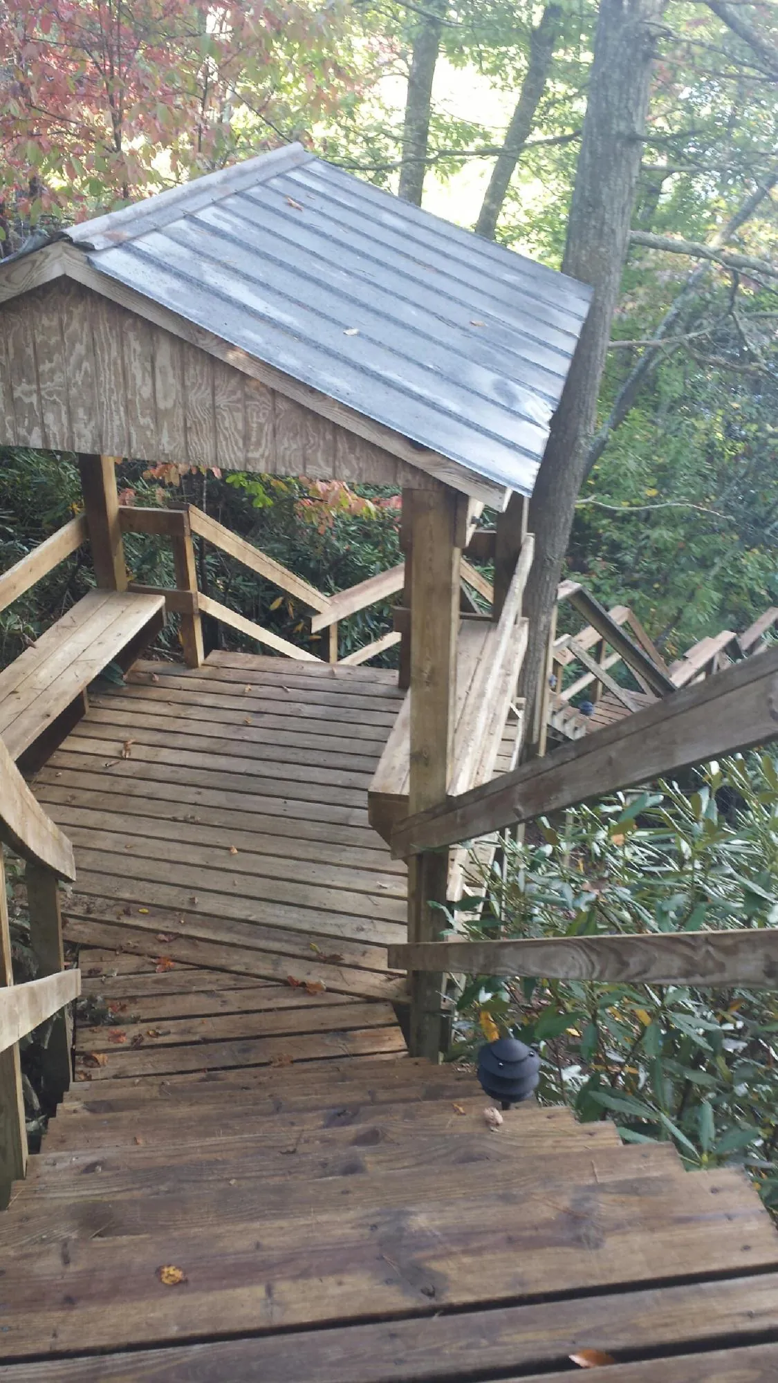 Metal roofed shelter over wooden steps on a wooded walkway — Skylight Repair & Installation work by our crew in Leslie