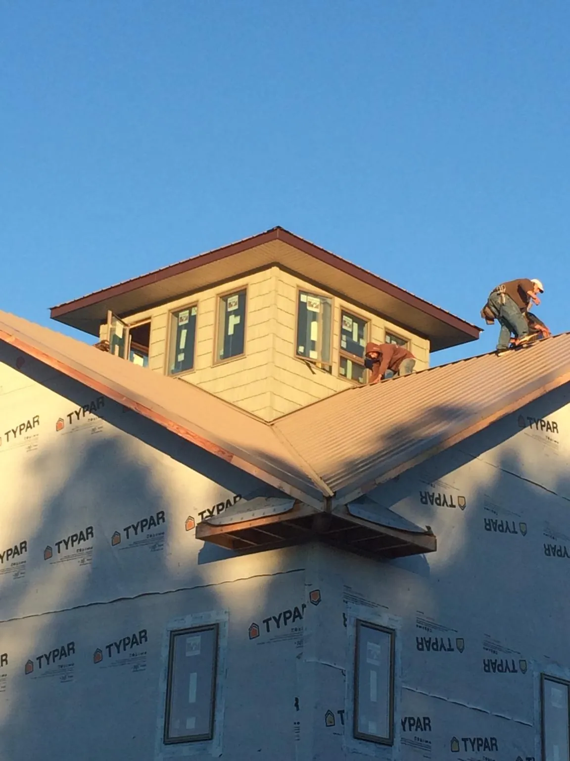 Roofers working around a rooftop cupola on a new metal roof at sunset — Roof Waterproofing in Leslie by Roofing Brothers
